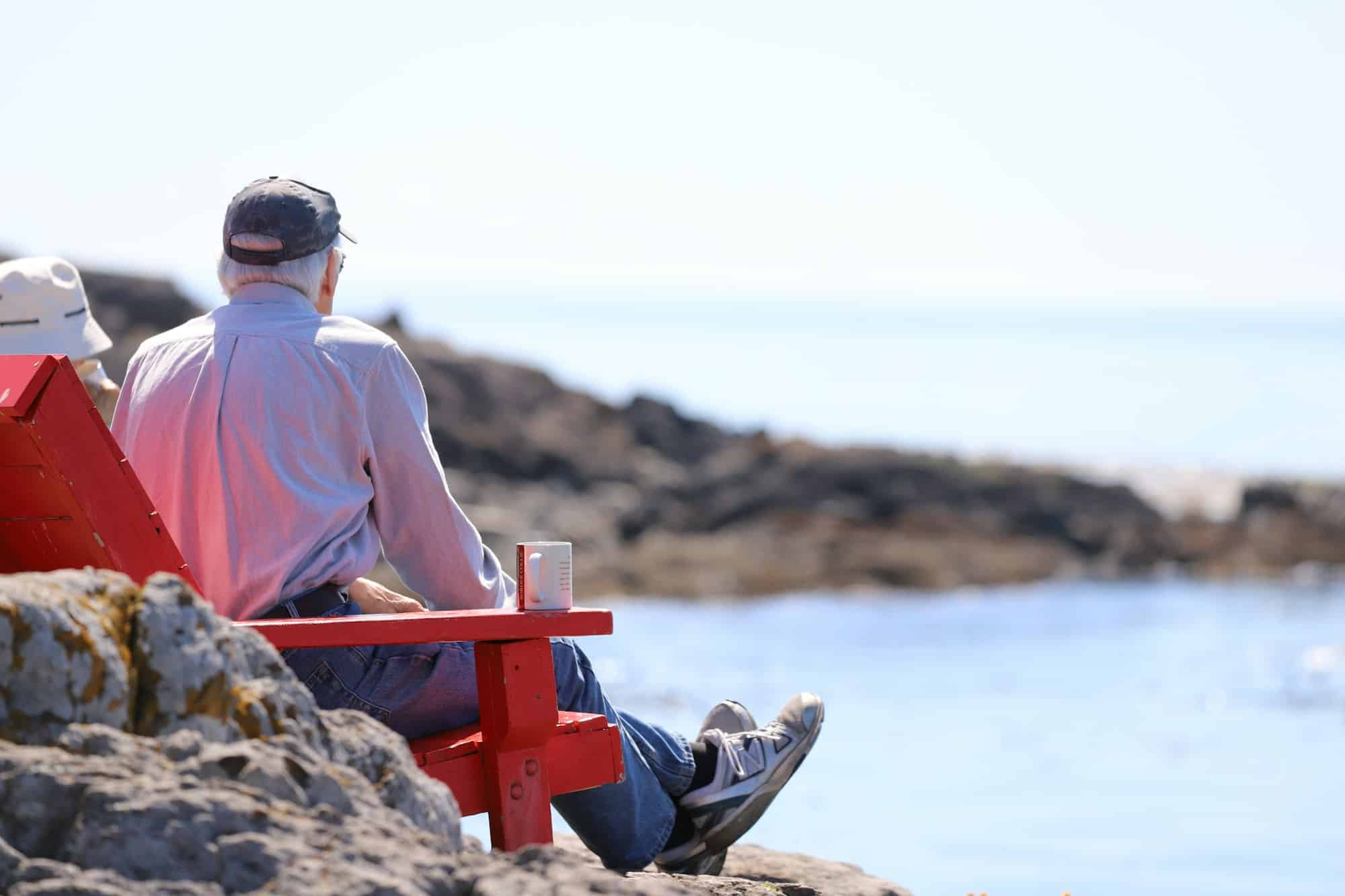 Old people on the chairs on rocky shore drinking coffee and enjoying the view